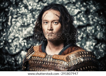 Close-up portrait of the ancient male warrior in armor holding sword. Historical character. Fantasy.