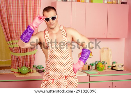 Handsome muscular man in an apron cooking in the pink kitchen. Love concept. Valentine\'s day.