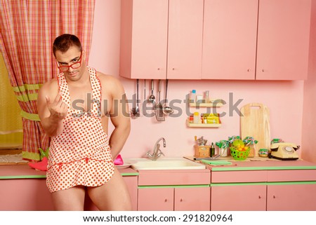 Handsome muscular man in an apron cooking in the pink kitchen. Love concept. Valentine\'s day.