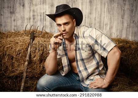Sexy cowboy smoking a cigar. Western style. Jeans denim fashion.