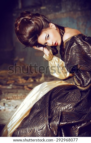 Art Fashion. Beautiful young woman in elegant historical dress and with barocco updo hairstyle posing in the ruins of the castle. Renaissance. Barocco.