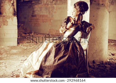 Art Fashion. Beautiful young woman in elegant historical dress and with barocco updo hairstyle posing in the ruins of the castle. Renaissance. Barocco.