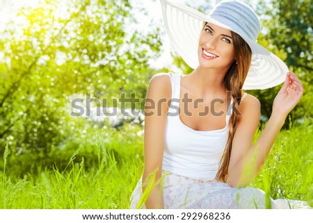 Portrait of a beautiful elegant young woman in light white dress and hat in the summer park. Beauty, fashion. Holidays.