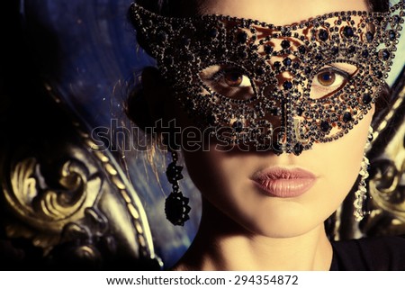 Close-up portrait of a beautiful woman in venetian mask. Carnival, masquerade. Jewellery, gems.