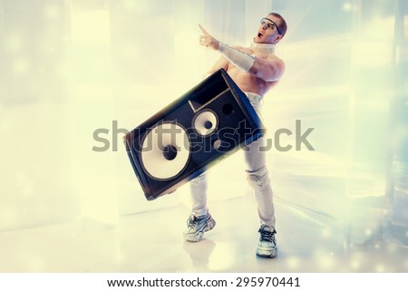 Futuristic muscular man dancing with huge music speakers on a luminous transparent background. Music, technology. Futuristic DJ.