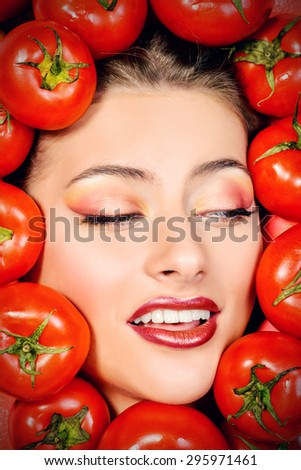 Close-up portrait of a beautiful smiling woman among the tomato. Healthy eating concept. Make-up, cosmetics.