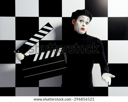 Movie actor and a mime posing with clapper board with different emotions. Chess board background. Cinema industry.