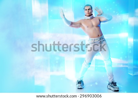 Technologies of the future, man of the future. Handsome muscular man with futuristic make-up stands on a luminous transparent background and touches something virtual.