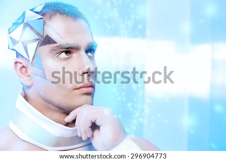 Close-up portrait of a handsome man with futuristic make-up and hairstyle standing on a luminous transparent background.