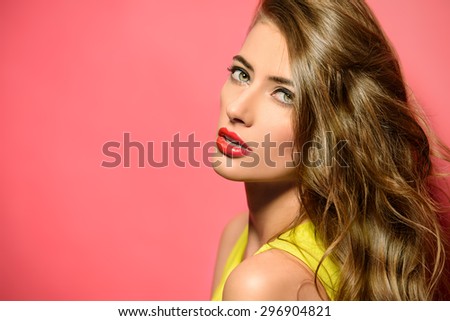 Fashion model in bright yellow dress posing over pink background. Beauty, fashion concept. Hair, healthy hair.