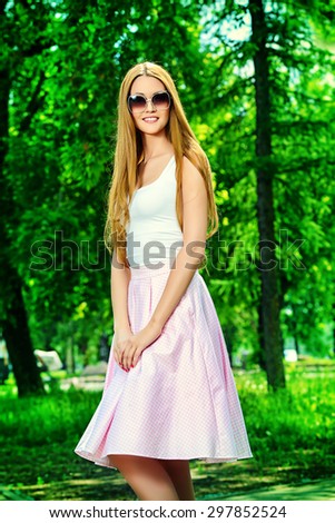 Portrait of a beautiful elegant woman in light summer clothes walking in the summer park. Beauty, fashion.