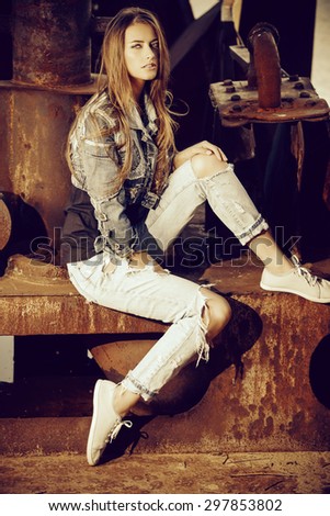 Stunning young woman in jeans clothes posing over urban background. Denim style. Fashion shot.