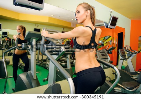 Attractive young woman is training on a treadmill in a fitness club. Active lifestyle, bodycare. Fitness equipment.