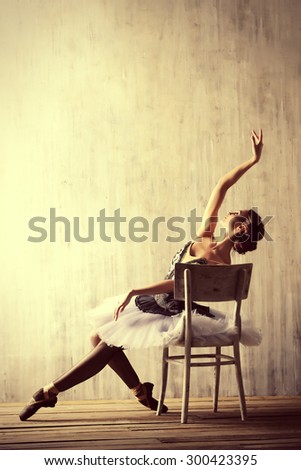 Professional ballet dancer posing at studio over grunge background. Art concept.