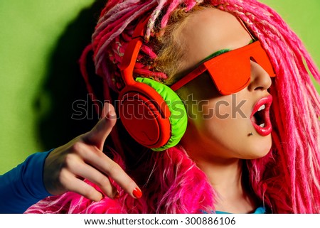 Modern party girl DJ in bright clothes, headphones and with bright dreadlocks. Disco, party. Show business. Bright fashion.