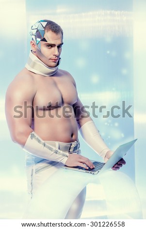 Handsome muscular man of the future wearing futuristic glasses working on a laptop. Technologies of the future.
