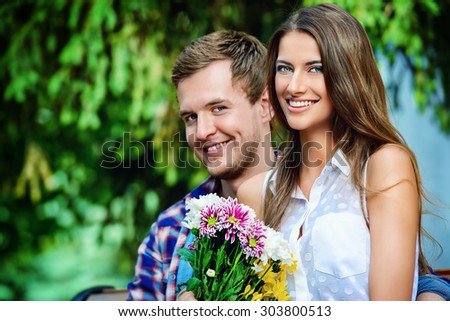 Young man giving flowers to his sweetheart girl. Sunny summer day.