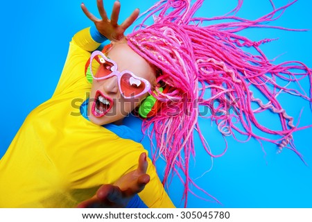 Crazy expressive trendy DJ girl in bright clothes, headphones and bright dreadlocks. Disco, party. Bright fashion.