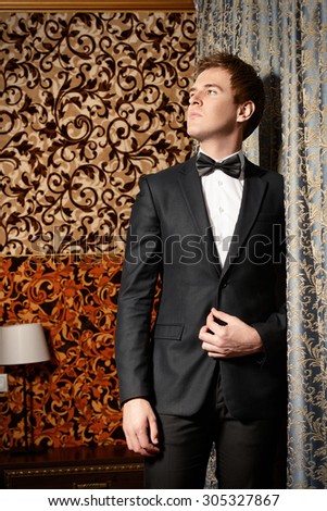 Vogue shot of a handsome man in black suit and bow-tie. Men\'s beauty, fashion.