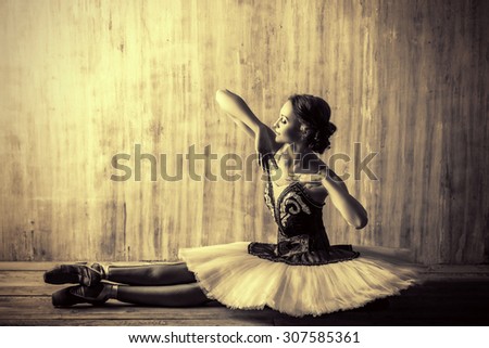 Professional ballet dancer posing at studio over grunge background. Art concept. Toned photo, vintage style.