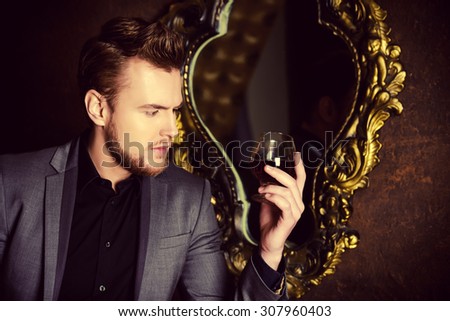 Elegant man in a suit with glass of beverage and cigar in vintage room. Fashion.