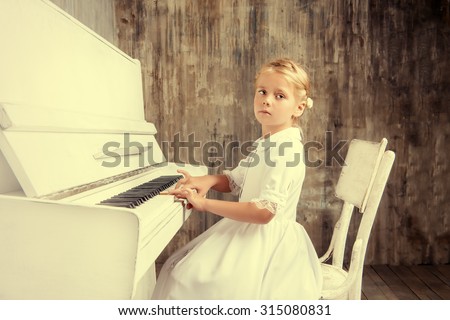 Romantic little girl in white dress playing the piano. Music and art concept. Retro style.