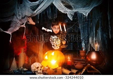 Scary funny boy in a costume of skeleton in a wizarding lair. Halloween party. Halloween decorations.
