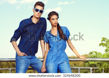 Fashion shot of an attractive young couple in jeans clothes posing outdoor.