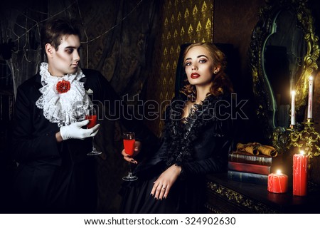 Beautiful man and woman vampires dressed in medieval clothing stand in a room of the old abandoned castle. Halloween.
