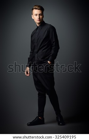 Full length portrait of a handsome male model in black clothes posing at studio. Men\'s beauty, fashion.