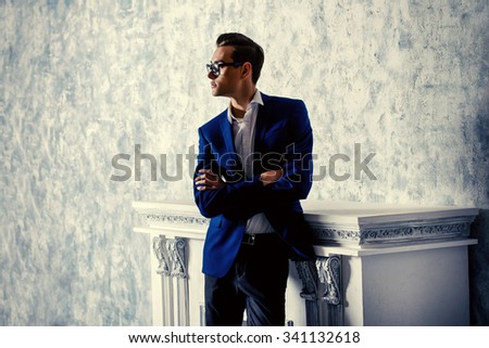 Vogue shot of a handsome elegant man in a suit posing in vintage interior. Men\'s beauty, fashion.