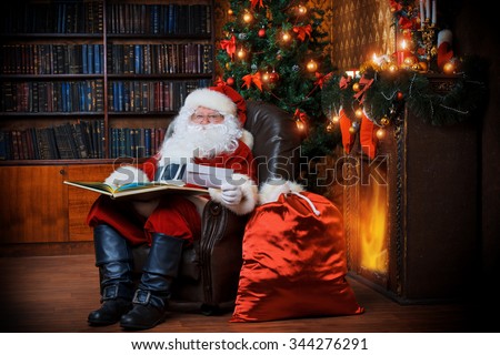 Santa Claus sitting at his home in a comfortable chair and reading a letter.