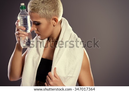 Beautiful athletic woman standing with white towel and clear water after exercise. Sports, healthcare.