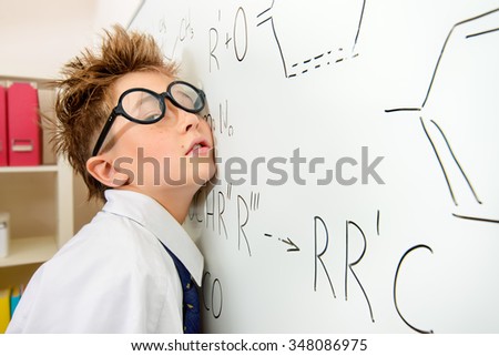 Funny schoolboy in big glasses standing by the school board. Chemistry. Science and education.