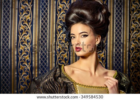 Baroque Style - beautiful young woman in elegant historical dress and with barocco hairstyle posing over vintage background. Renaissance. Barocco. Fashion.