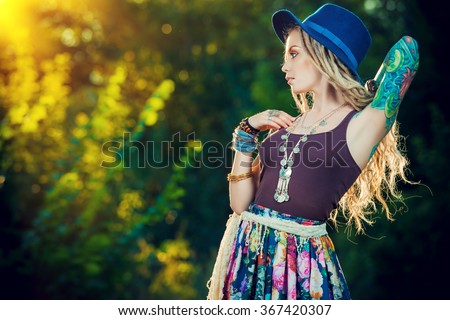 Boho style fashion. Beautiful young woman wearing boho style clothes posing in the rays of the evening sun, sunset.