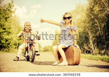 Happy kids go on a journey on a motorcycle on a bright sunny day. Adventure. Friendship. Summer holidays.
