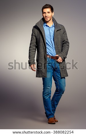 Full length portrait of a handsome man wearing jeans clothes and a coat. Men's beauty, seasonal fashion. Studio shot.