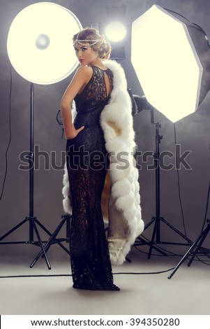 Stunning beauty model posing at studio in light flashes. Professional fashion model. Celebrity. Full length portrait.