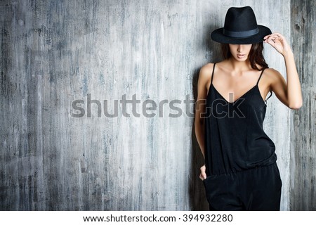 Studio shot of a magnificent young woman in elegant black clothes and classic hat. Beauty, fashion concept.