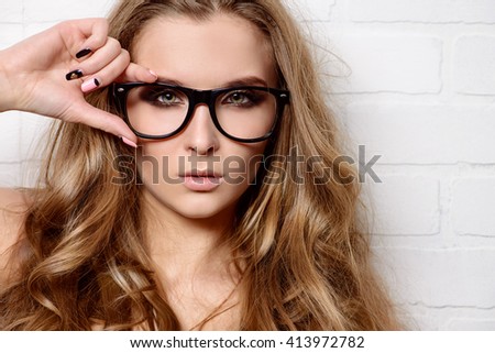 Optics style. Beautiful sexy girl with long wavy hair wearing glasses. Fashion shot.