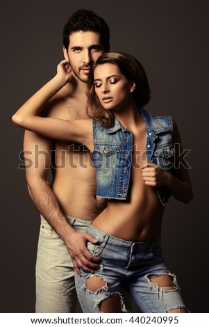 Beautiful sexual couple topless playing in love games. Jeans style. Studio shot.