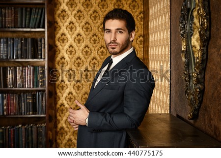 Respectable young man standing by a fireplace in a room with classic interior. Luxury. Men\'s beauty, fashion.