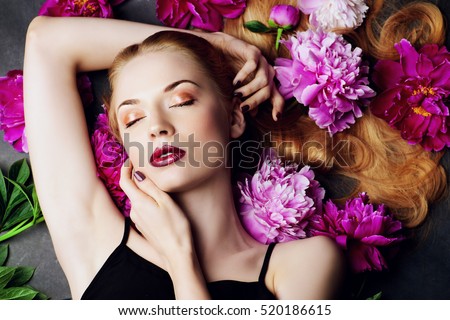 Beauty portrait. Beautiful blonde woman with sensual maroon lips lying among peony flowers. Cosmetics, make-up. Perfumery.