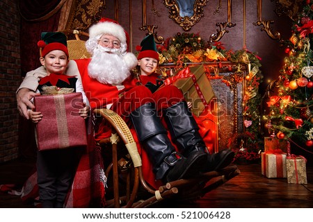 Santa Claus and the elves children with gift boxes. Miracles on Christmas.
