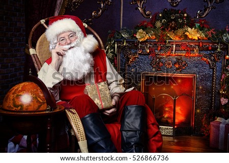 Christmas, tourist trip concept. Santa Claus at his home beautifully decorated for Christmas making plans of travelling around the planet. Christmas time. Time for miracles.