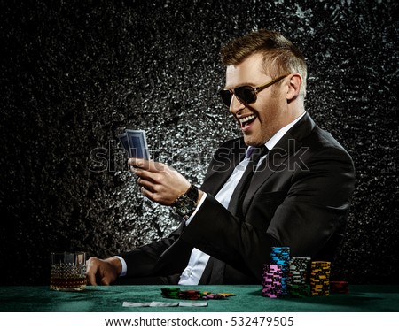 A wealthy mature man drinking brandy and playing poker with the excitement in a casino. Gambling, playing cards and roulette.