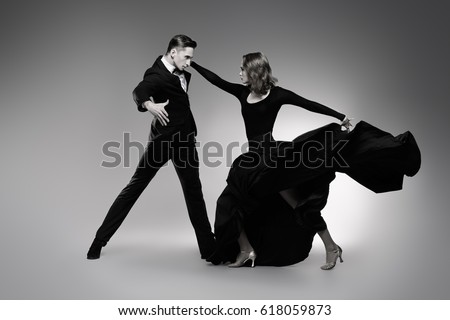 Black-and-white portrait of professional dancers performing tango. Beautiful young people in love dancing on a date. Studio shot.