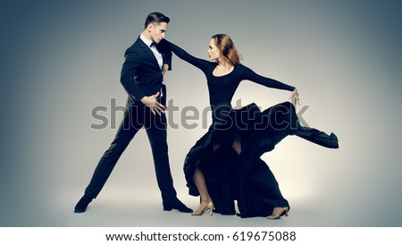 Couple of professional dancers performing tango. Beautiful young people in love dancing on a date. Studio shot.