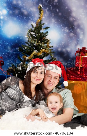 Christmas theme: happy family in Santas caps sitting together on a snow.